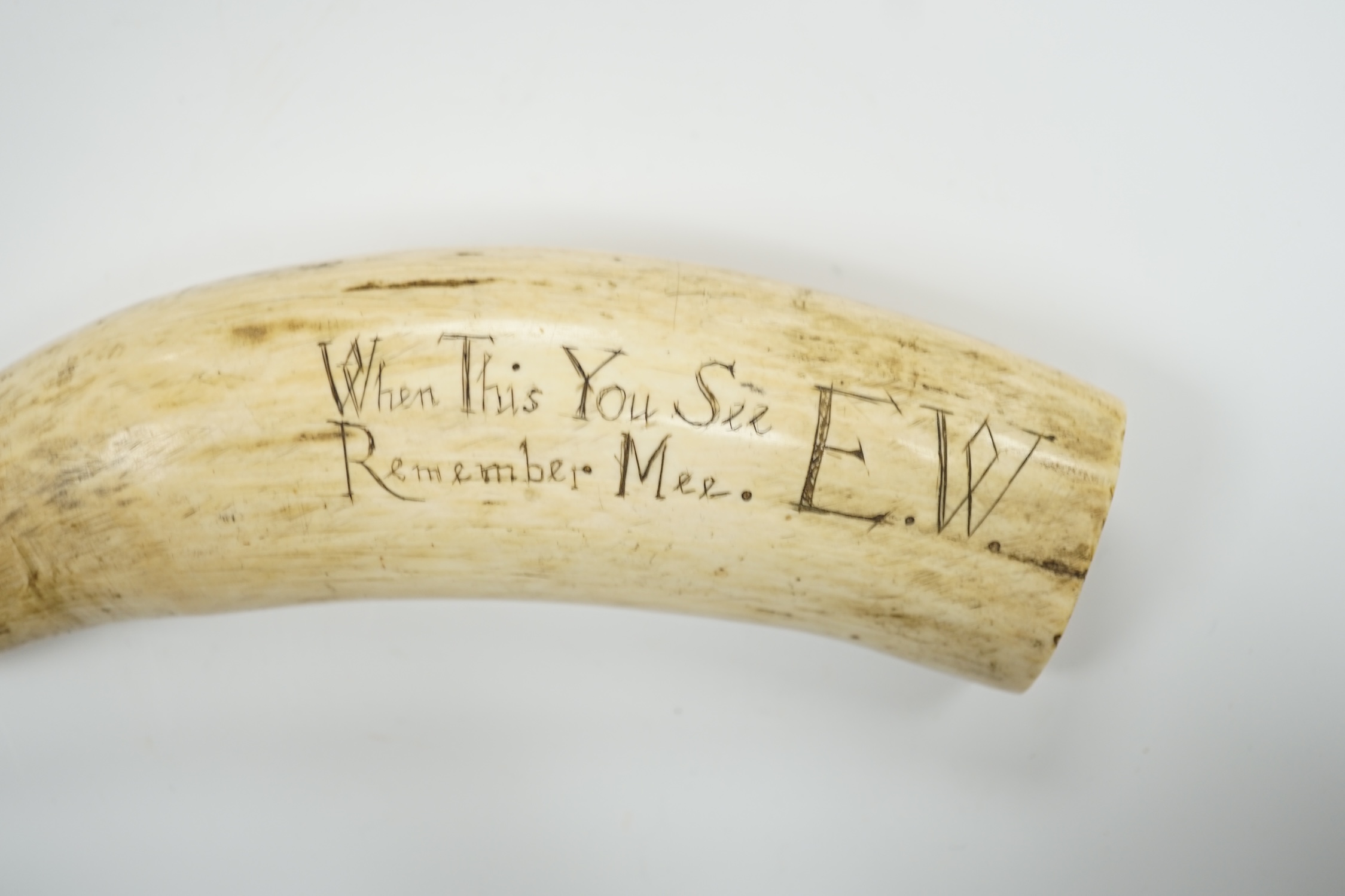 A 19th century Scrimshaw walrus tooth with carved motto ‘When this you see, remember mee’ and initialled E.W, 16cm in length